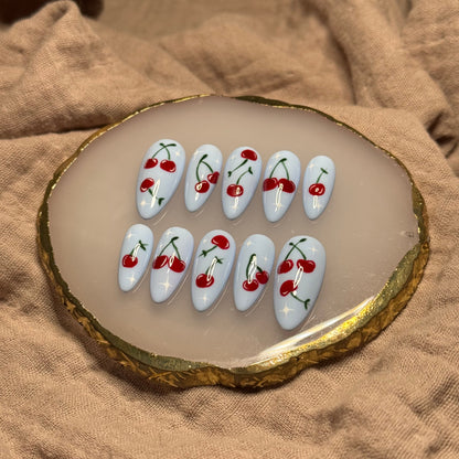 handmade light blue press on nails with deep red cherry designs and light star accent nails, reusable, custom handmade press on nails, easy at-home manicure