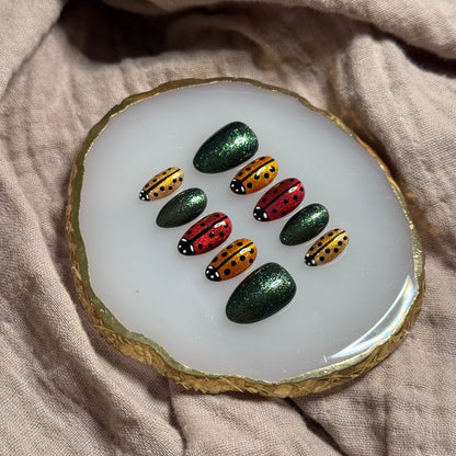 handmade sparkly gold, orange and red press on nails with lady bug designs and deep green accent nails, reusable, custom handmade press on nails, easy at-home manicure